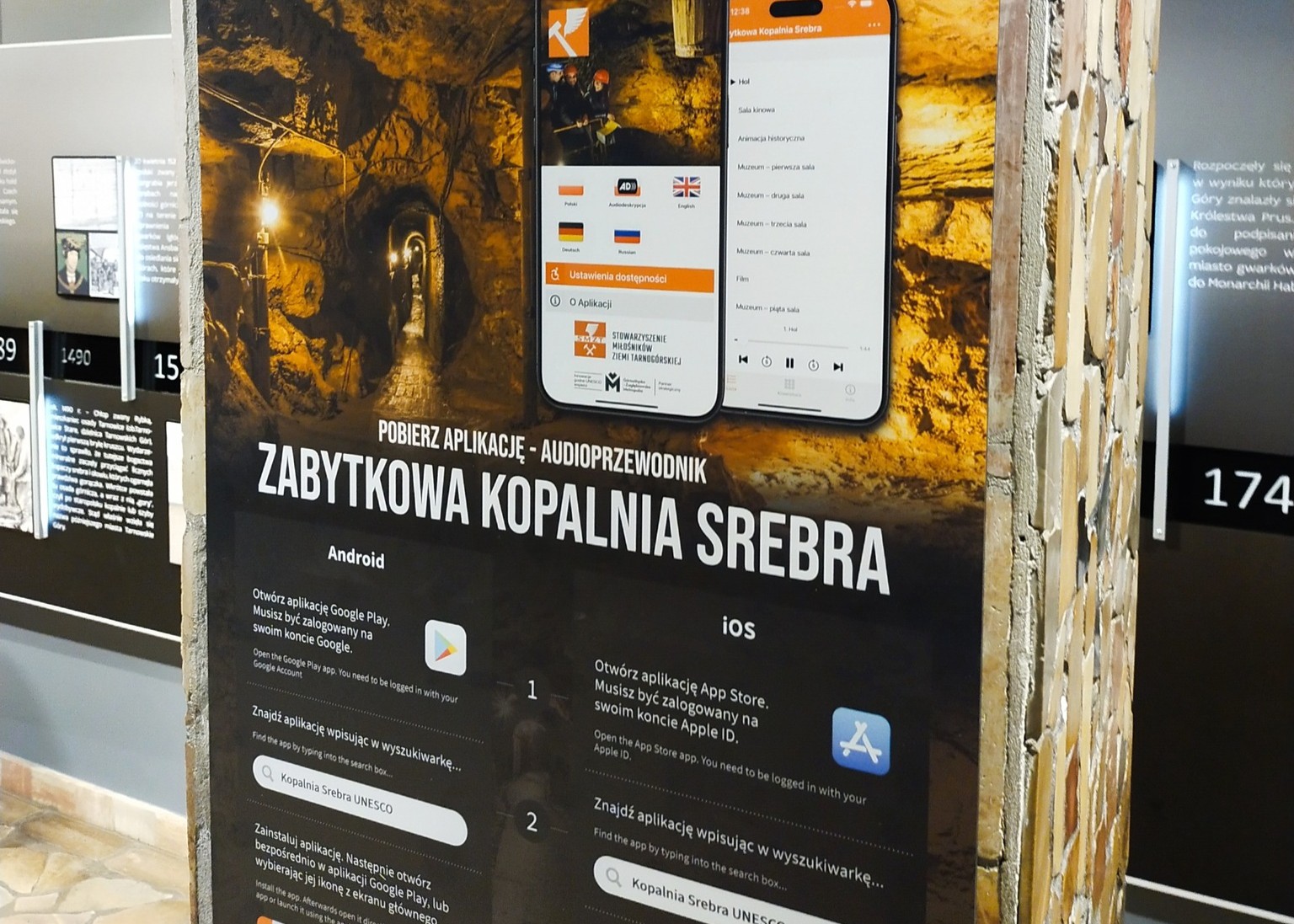 Na zdjęciu plakat w obiekcie z instrukcją, jak pobrać audioprzewodnik na swój telefon.