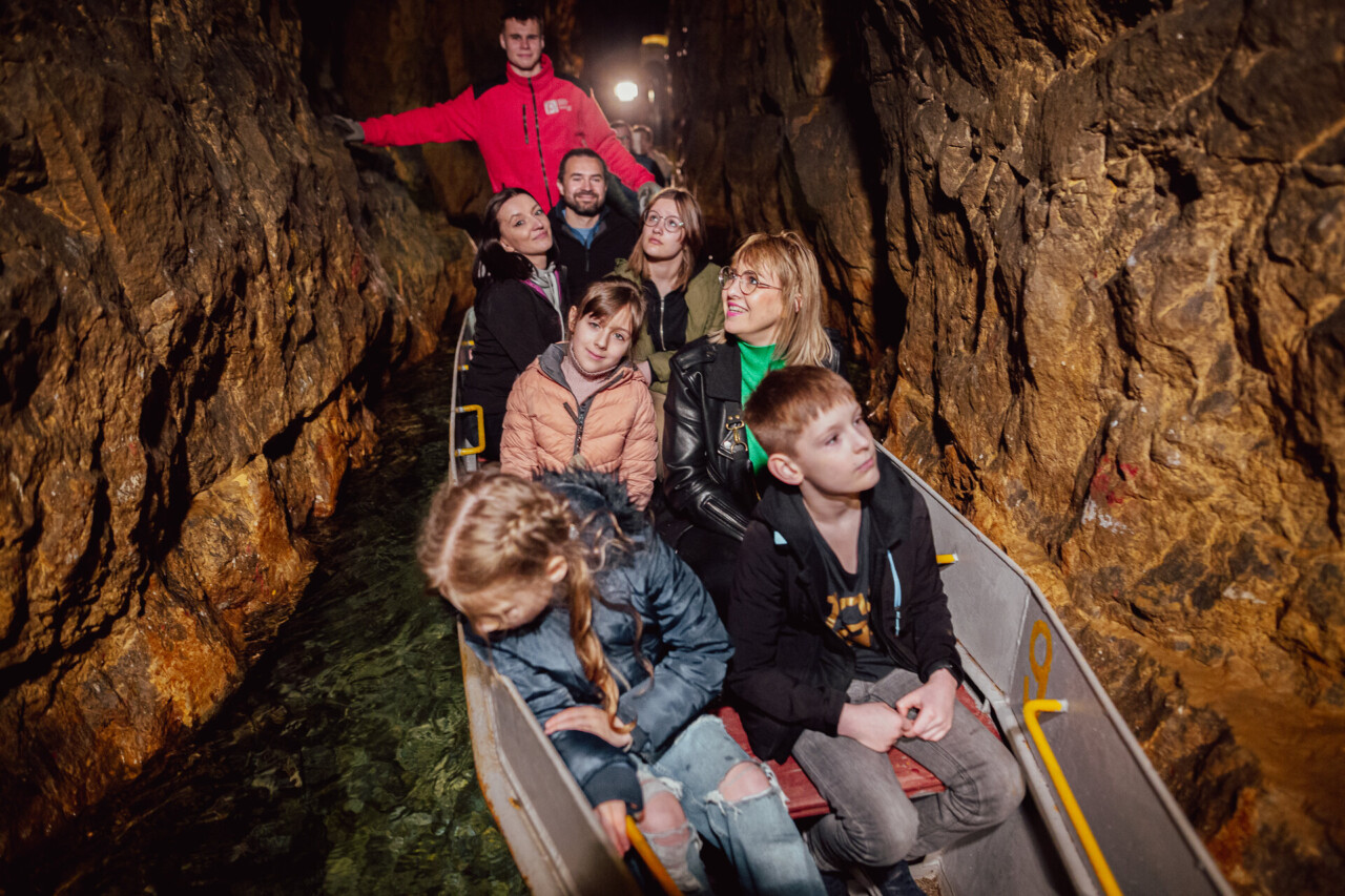 Turyści płynący łodziami w Sztolni Czarnego Pstrąga