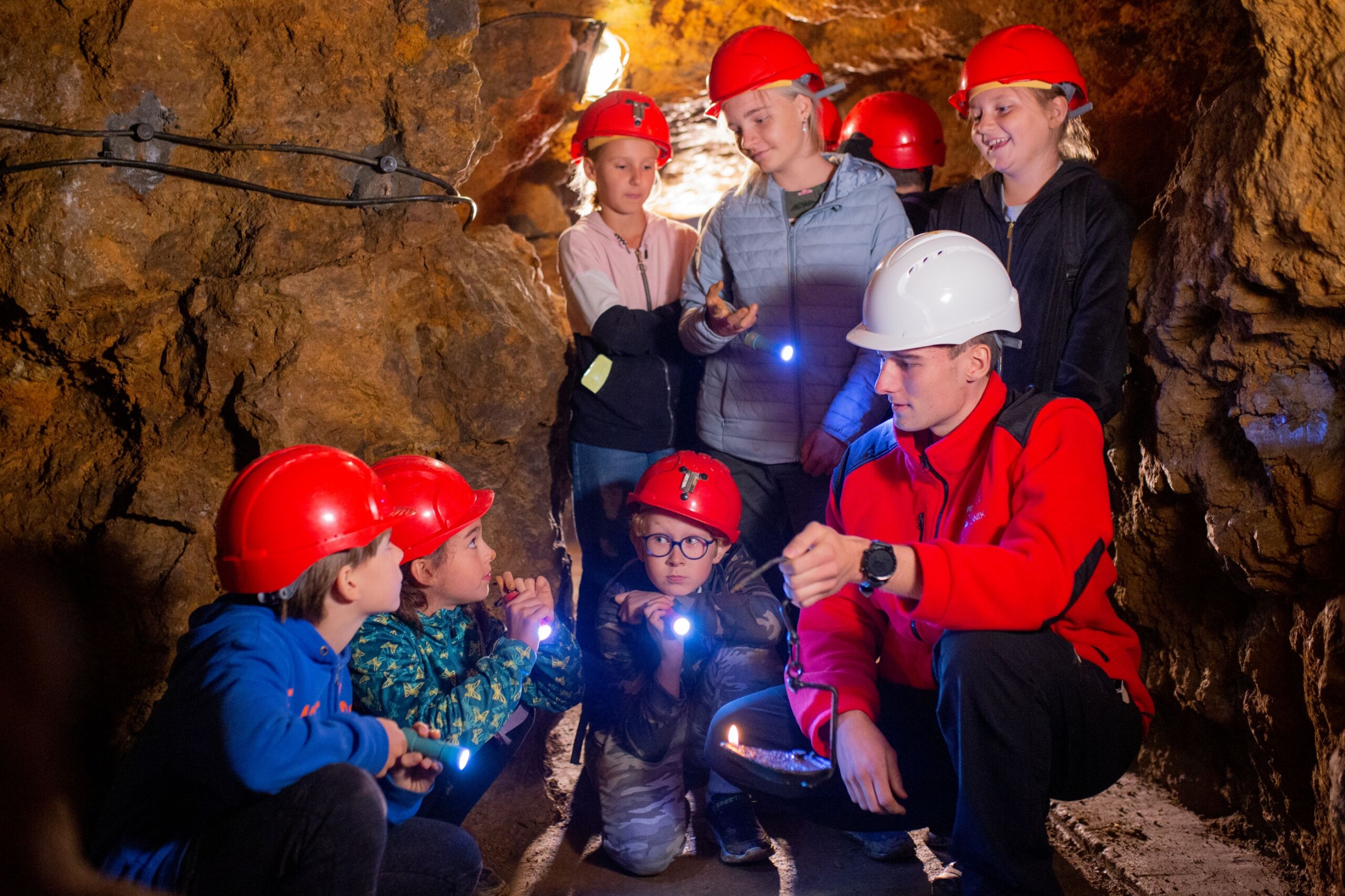 Grupa dzieci i przewodnik w podziemiach Zabytkowej Kopalni Srebra
