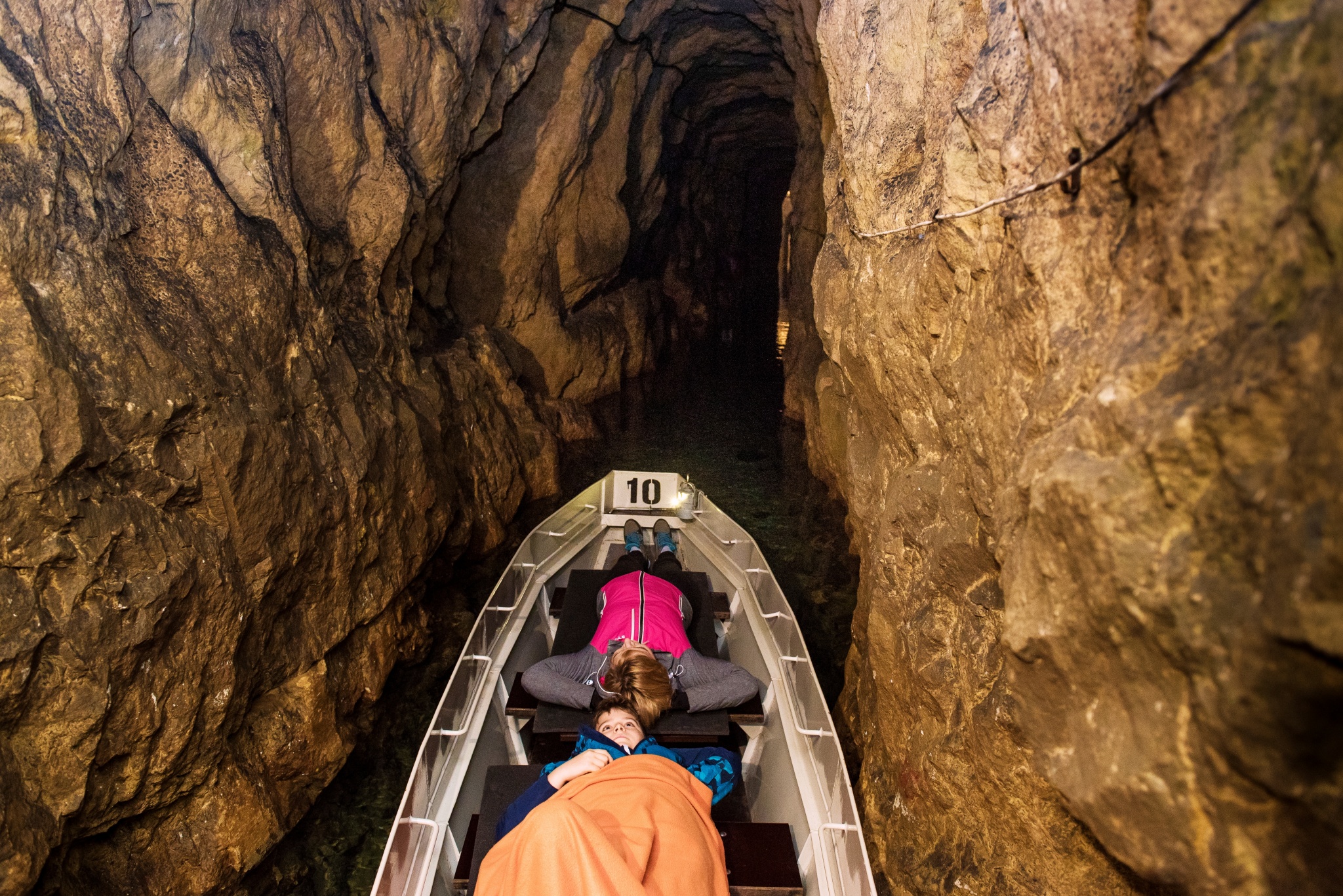 dwie osoby płynące łodzią w sztolni