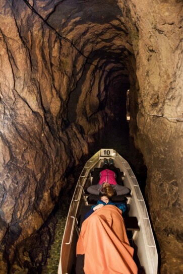 dwie osoby płynące łodzią w sztolni