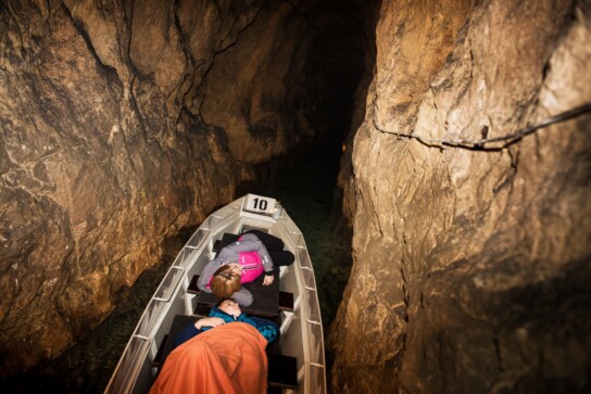 dwie osoby płynące łodzią w sztolni