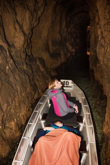 dwie osoby płynące łodzią w sztolni