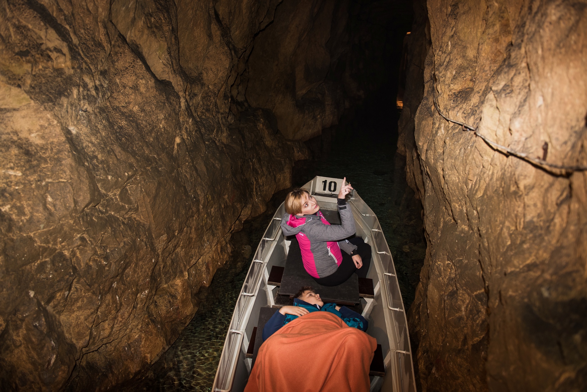dwie osoby płynące łodzią w sztolni