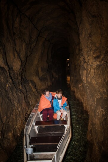 dwie osoby płynące łodzią w sztolni