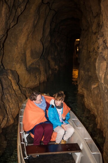 dwie osoby płynące łodzią w sztolni