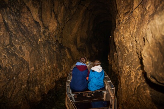 dwie osoby płynące łodzią w sztolni