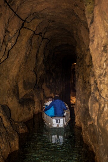 dwie osoby płynące łodzią w sztolni